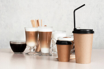 Disposable Paper cups on the table on a background of cups with different coffee drinks