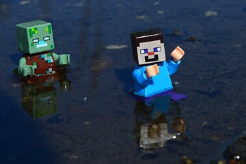 Fototapeta premium Minecraft LEGO figure of drowned zombie mob chasing scared figure of Steve in shallow waters, daylight sunshine.