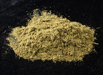 pile of powder of stevia rebaudiana herb on black
