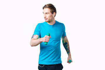 sports man in a blue t-shirt with dumbbells in his hands fitness exercises tattoo