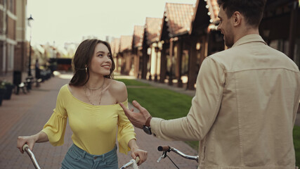 happy man and woman talking near bicycles on street.