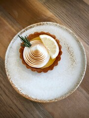 Top view lemon cheese tart on white ceramic plate on wooden table in coffee cafe. .