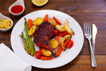 Homemade Baked Chicken Drumstick with Potatoes in a white plate on an old wooden table.