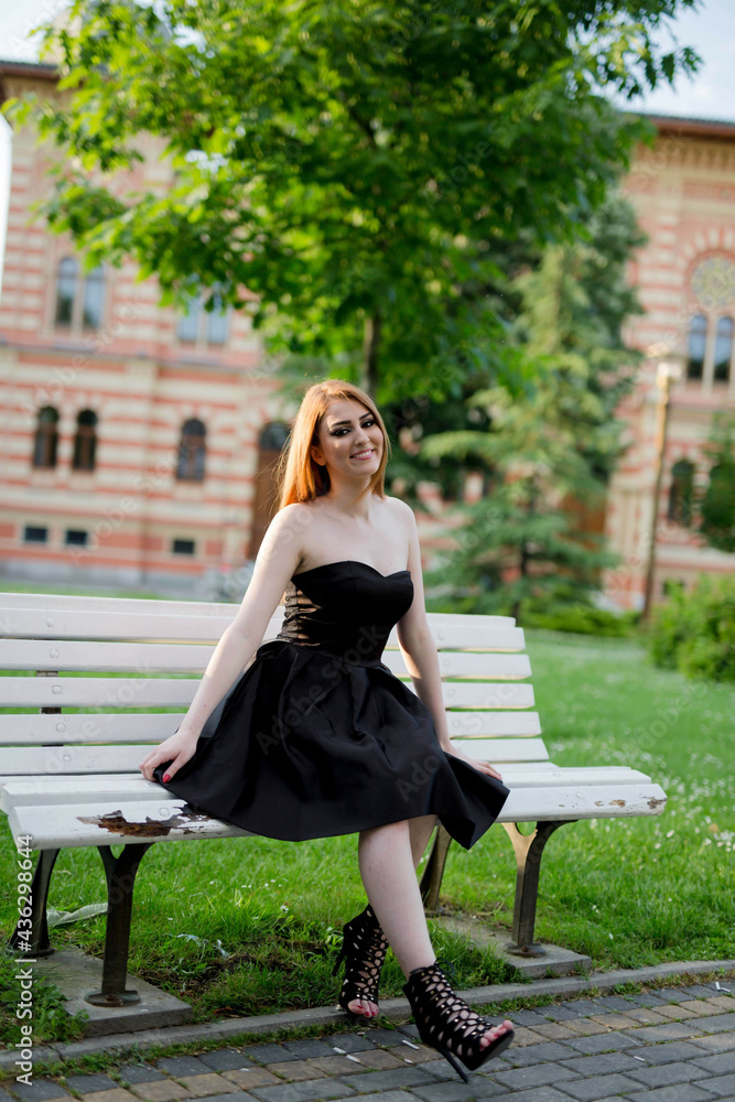 Poster vertical shot of a white caucasian woman wearing a classy black dress and posing for a picture