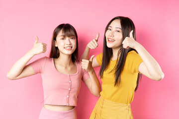 Portrait of two beautiful young Asian girls posing on pink background