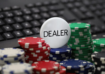 dealer chip on poker chips in front of computer keyboard, concept image of online casinos, gambling addiction on the internet