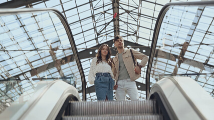 low angle view of couple near escalator in shopping center.