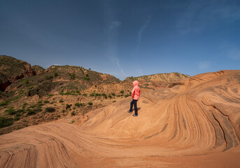 A woman stand on the wave landform rocks