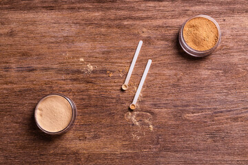 Mineral powder of different colors with a spoon dispenser for make-up on wooden background