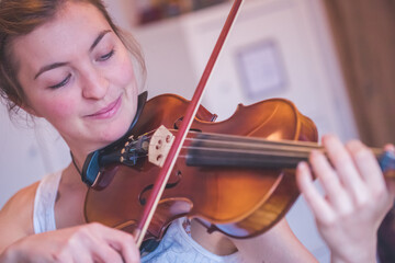 Practicing classical music and violin concept: Young girl happily plays on her violin