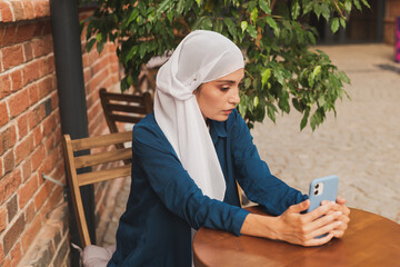 Happy muslim woman having video call on smartphone in city