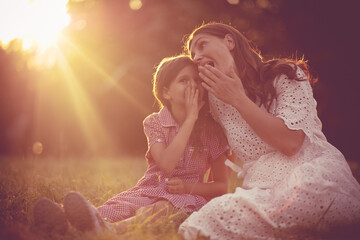 Mother and daughter sitting on grass and talking.