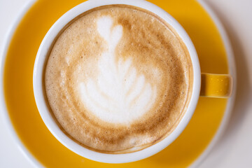 Close up yellow cup of delicious cappuccino on a white background.
