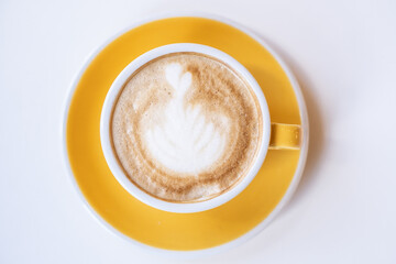 Close up yellow cup of delicious cappuccino on a white background.
