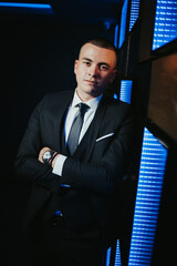 Vertical shot of a young attractive male in a formal suit posing in a nightclub