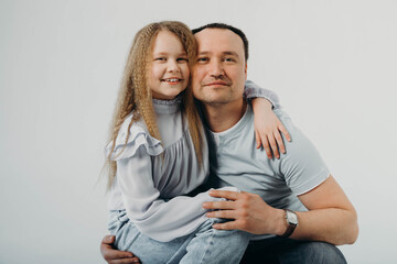Portrait of a little smiling blonde daughter hugging her father, laid her chin on her father's head. Family values. Father's day.