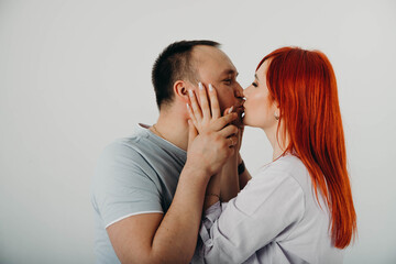Young couple in love on a white background. A young girl with red hair looks in love at her blonde boyfriend.
