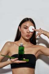 Fototapeta premium Cheerful young asian woman holding cotton pad