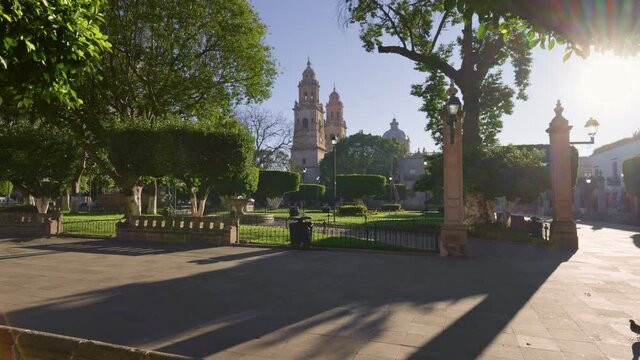 City center in Morelia. Green Park and Cathedral in Marelia, Michoacan, Mexico. Sun breaks through the tree illuminating park and the ancient cathedral