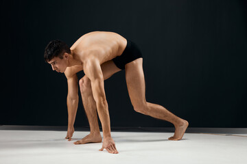 Obraz na płótnie Canvas handsome male bodybuilder in black shorts on a dark background