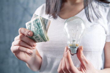 young woman holding a light bulb and dollar bills. c