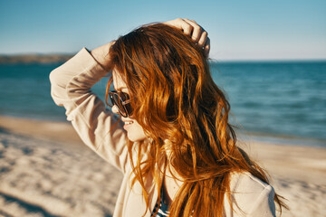 happy traveler on the beach near the sea red hair beige coat sand island