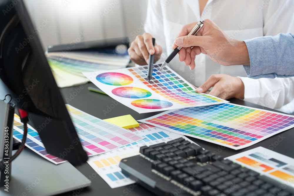 Poster graphic designer or creative working together coloring using graphics tablet and a stylus at desk wi
