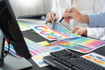 Graphic designer or creative working together coloring using graphics tablet and a stylus at desk...