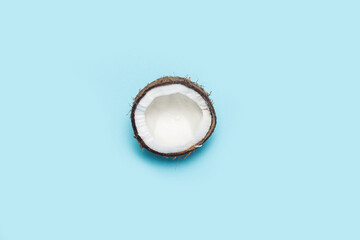 split half of a coconut on a blue background. Top view, flat lay