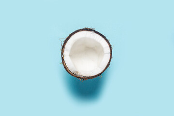 split half of a coconut on a blue background. Top view, flat lay