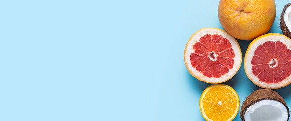 exotic fruits on a blue background. Coconut, orange, grapefruit are cut. Top view, flat lay. Banner