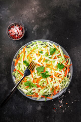 Coleslow cabbage salad with carrot on grey kitchen table. Top view, copy space