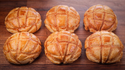 Closeup of freshly baked pineapple buns on a wooden board in a kitchen