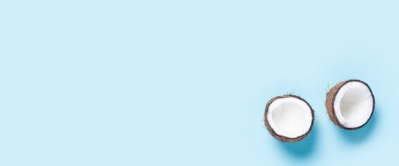 open coconut two halves on a blue background. Top view, flat lay. Banner