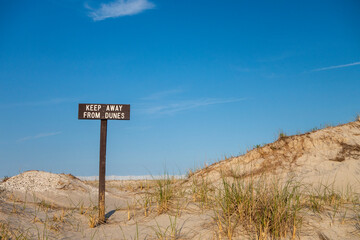 Sand dunes with wooded sign reading keep away from dunes