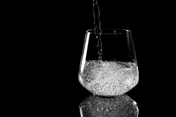 pouring pure mineral water into a glass beaker on a black background