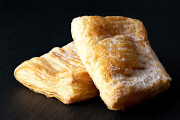puffs with filling and icing sugar on a black background