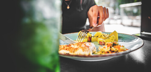 woman hand holding fork and knife eat chicken breast meat with potato in a plate