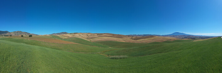 180 degree saerial photo of the wheat fields in the heart of Sicily in the Erei mountains. Sicilian wheat cultivation. Small rural villages of Ramacca and Raddusa. Hay and grain. Etna view.