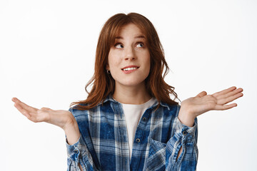 I dont know. Confused redhead girl shrugging and looking up with indecisive, unsure face, cant make decision, have no clue, standing puzzled against white background