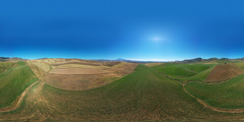 360 degree aerial photo of the wheat fields in the heart of Sicily in the Erei mountains. Sicilian wheat cultivation. Small rural villages of Ramacca and Raddusa. Hay and grain. Etna view.