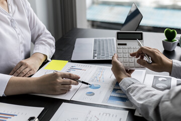 Two businessmen are meeting on corporate finance, a businessman holding a white calculator and calculating the numbers on a document to verify accuracy together with a businesswoman. Company finance.