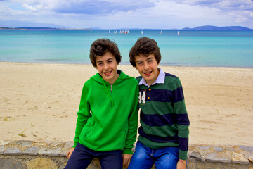Fototapeta na wymiar happy twins smiling at camera on the beach in cesme