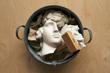 Broken plaster head in a metal basin. Headache, mental illness, depression concept