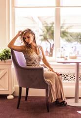 Gorgeous young blonde Caucasian woman in a ball gown ready for romantic dinner in hotel restaurant