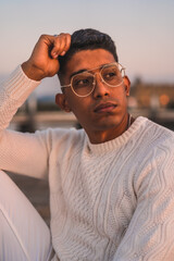 Summer lifestyle, a young Latino enjoying summer vacations. dressed in white with pants and sweater, enjoying the sunset