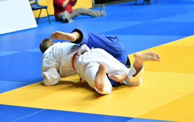 Two Boys judoka in kimono compete on the tatami 