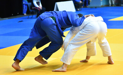 Naklejka premium Two Boys judoka in kimono compete on the tatami 