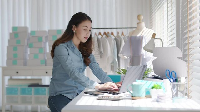 Young asia people woman female e-commerce parcel work check typing talk to customer on notebook for box shipping online fulfillment sme dropshipping digital dispatch app clothes fashion supply chain.
