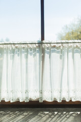 Light sheer curtain with lace on the window. Sunlight shines through the curtain